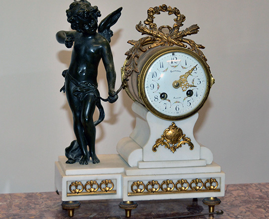 Lot 410: 19th c Louis XVI white marble mantle clock with bronze statue of Cupid beside mouvement by Butneau,Autun. H31cm.