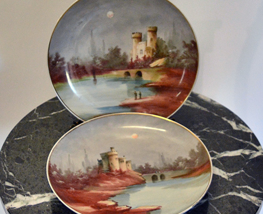 Lot 432: Pair early cent Montigny hand painted plates with caste by countryside scene. Dia 28cm.