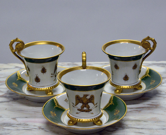 Lot 479: Three gilt rimmed cups & saucers with Empire eagle & bee emblem ( symbols that replaced the monarch lily flower).